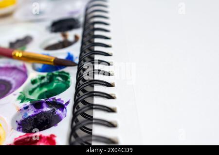 Close up view of a spiral bound notebook of watercolor paper.  Watercolor paints blurred in the background. Stock Photo