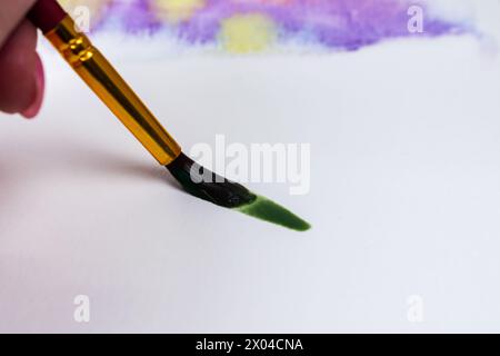 Artist practices basic wet on dry technique: wet paint on dry paper. Stock Photo