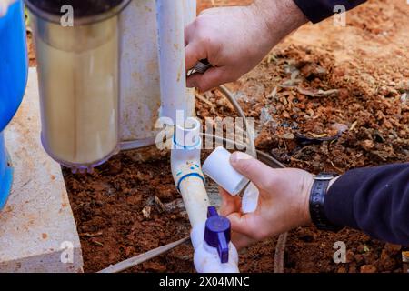As part of repair work, technician plumber uses clear primer for PVC pipe with before gluing pipes Stock Photo