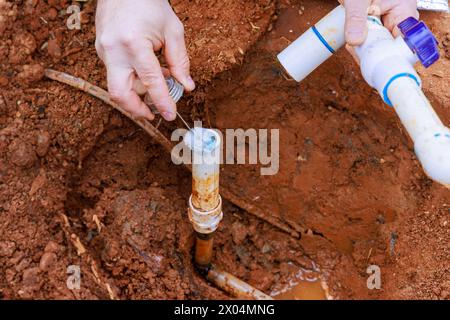 Plumber technician uses clear primer before gluing PVC pipe as part of repair process Stock Photo