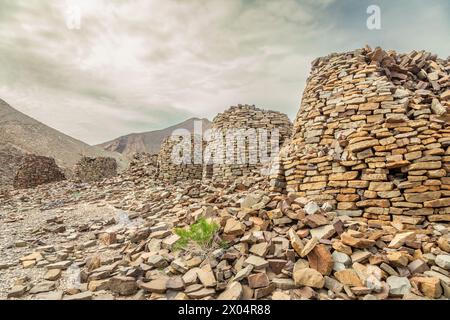 Ancient stone beehive tombs with Jebel Misht mountain in the background, archaeological site near al-Ayn, sultanate Oman Stock Photo
