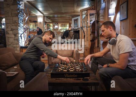 Men playing chess in a cozy, rustic room with unique set, Waterloo label. Stock Photo