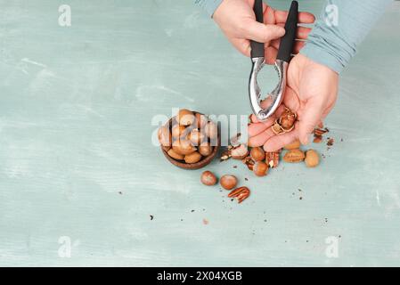 Crack nuts with a nutcracker, mix variety of almonds, hazelnuts and pecan nuts, healthy food and lifestyle Stock Photo
