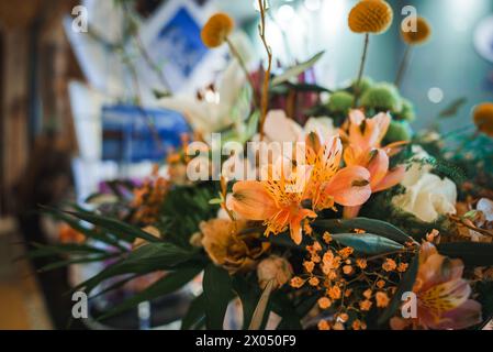 Vibrant Orange Lily Floral Arrangement with Yellow Flowers on Blurred Indoor Background Stock Photo