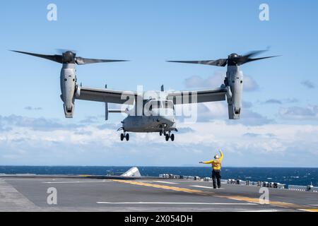 Aviation Boatswain’s Mate (Handling) 2nd Class Johnny Snowden, assigned to the Wasp-class amphibious assault ship USS Boxer (LHD 4), and a native of Atlanta, directs an MV-22B Osprey, attached to Marine Tiltrotor Squadron (VMM) 165 (Reinforced), 15th Marine Expeditionary Unit (MEU), to land on the flight deck during flight operations in the Pacific Ocean, April 5, 2024. VMM-165 (Rein.) is conducting deliberate, progressive training focused on the integration of MV-22s to the 15th MEU's Marine Air-Ground Task Force as pilots and air crews achieve proficiency. Boxer is the flag ship of the Boxer Stock Photo