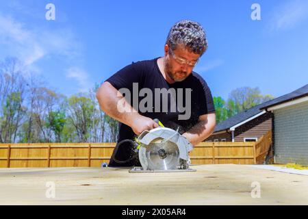 Using handsaw, carpenter trims plywood boards Stock Photo