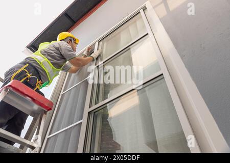 Construction worker repairing the sliding window. Open cap of adjust rail wheel. Stock Photo