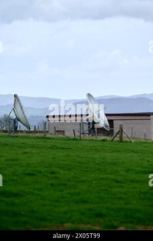 Two old satellite dishes in green field in England Stock Photo