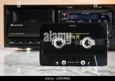 Sony UX-PRO 74 audio cassette standing in front of a cassette deck on a polished marble tabletop with reflection Stock Photo