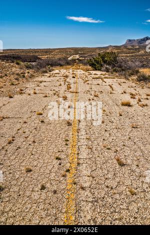 Abandoned section of US-180, US-62 highway with overgrowth, Guadalupe Mountains in distance, Texas, USA Stock Photo