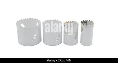 a set of 4 used round hole metal saw blades standing upright used with a drill for cutting opening in wood isolated on white background Stock Photo