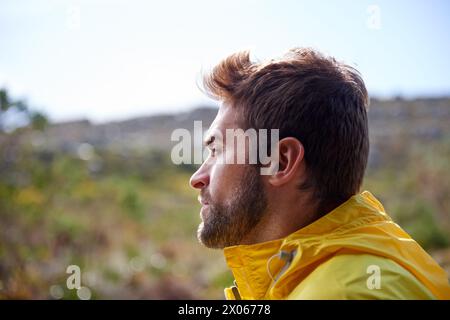 Man, waterproof jacket and nature for outdoor recreation, activity or holiday. Male traveler or tourist and watch scenic view on adventure in cold Stock Photo