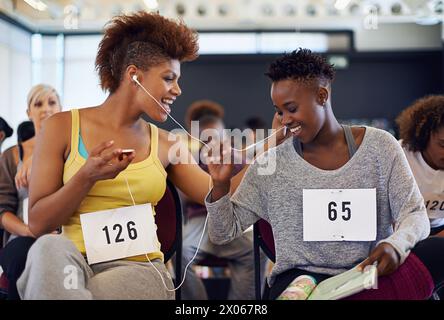 Happy and women dancers in portrait, listening to music and waiting for dance audition or performance. African friends, bonding and phone for Stock Photo
