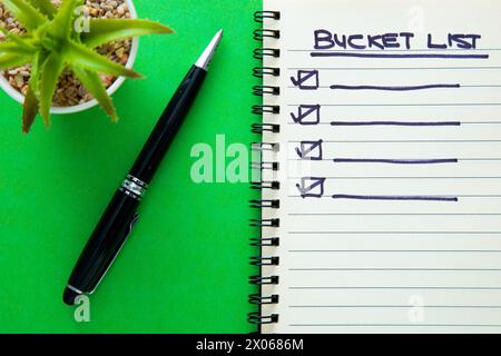 Bucket list on notebook with a pen on green background Stock Photo