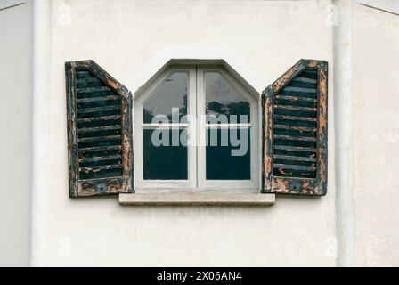 unusual small window shape with worn wooden shutters of an ancient palace in Prague Stock Photo