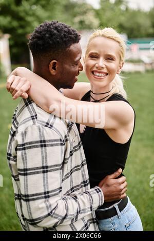 A happy couple, consisting of an African American man and a Caucasian woman, embracing lovingly in a vibrant park setting. Stock Photo