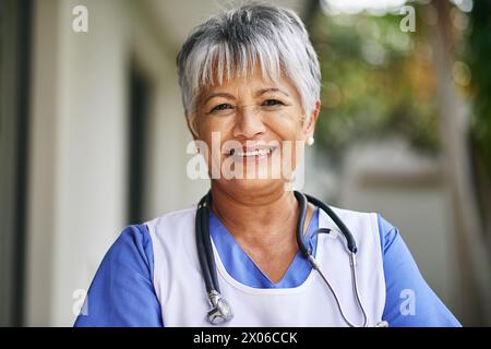 Face, woman and senior nurse with pride outdoor for healthcare, hospice and sick. Medical care, stethoscope and Portrait of mature female worker at Stock Photo