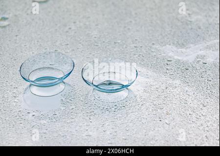 Contact lenses, on mirror surface, with water drops. Stock Photo