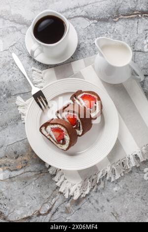 Homemade cake roll with strawberry and cream cheese closeup on a marble background. Vertical top view from above Stock Photo