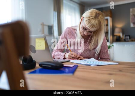 Young sick freelance business woman working at home, work on laptop computer. Online remote working, female wireless connection with company, doing di Stock Photo