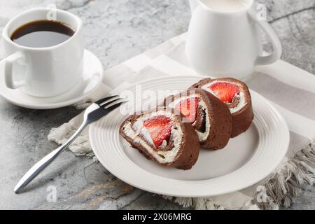 Chocolate cake roll with fresh strawberries and cream cheese closeup on a marble background. Horizontal Stock Photo