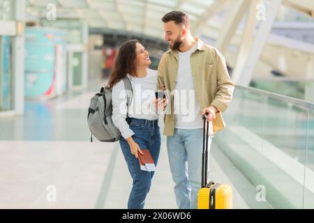 Man and Woman Walking Through Airport With Luggage Stock Photo