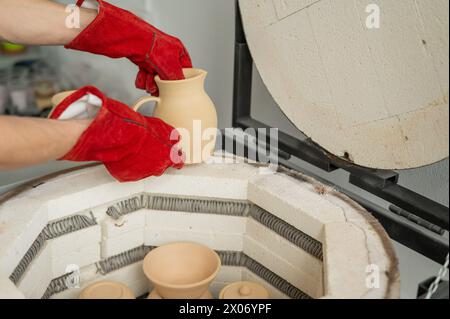 Close-up of a man's hands loading ceramics into a special kiln.  Stock Photo