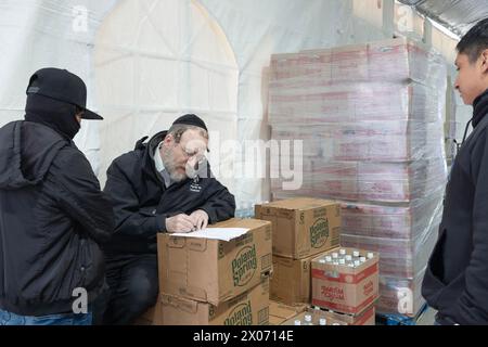 An orthodox Jewish manager at a kosher supermarket instructs 2 young Hispanic men on his staff. In Brooklyn, New York Stock Photo