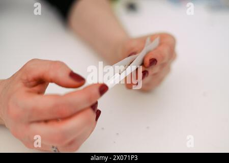 unrecognizable female young adult person prepare smoke hashish tobacco cigarette joint with filter at home on white table for personal health relax us Stock Photo