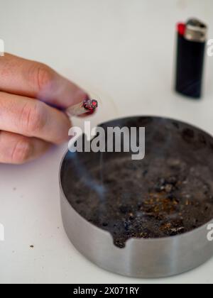 unrecognizable female young adult person prepare smoke hashish tobacco cigarette joint with filter at home on white table for personal health relax us Stock Photo