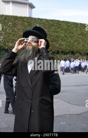 A rabbi at a Hasidic parochial school watches the 2024 Solar eclipse from the yeshiva's schoolyard. In Rockland County, New York. Stock Photo