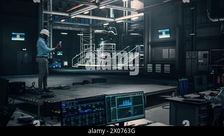 Male Engineer Uses Tablet Computer while Working in an Industial Facility at a Factory. Scientist uses Augmented Reality Software. Empty Space Left for Mock Up Template for VFX. Stock Photo