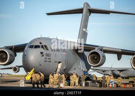 U.S. Airmen with the 21st Airlift Squadron greet and unload equipment from a C-17 Globemaster III on the flightline at Travis Air Force Base Stock Photo