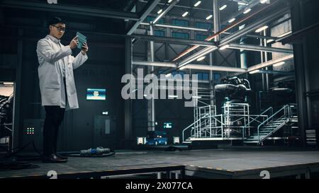 Male Engineer Uses Tablet Computer while Working in an Industial Facility at a Factory. Scientist uses Augmented Reality Software. Empty Space Left for Mock Up Template for VFX. Stock Photo