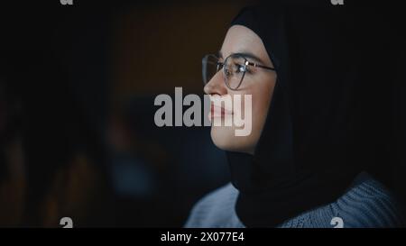 Beautiful Close Up Portrait of a Multiethnic Muslim Female Wearing Hijab and Glasses, Charmingly Smiling and Posing on Camera. Happy Diverse Young Woman in Casual Clothes Indoors. Stock Photo