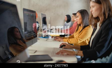 Diverse Multiethnic Group of Female and Male Students Sitting in College Room, Learning Computer Science. Young Scholars Study Information Technology on Computers in University, Writing Code in Class. Stock Photo