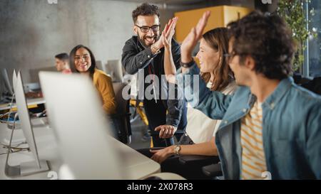 Lecturer Helps Scholar with Project, Advising on Their Work. Teacher Giving High Five to Diverse Multiethnic Group of Female and Male Students in College Room, Teaching Software Engineering. Stock Photo