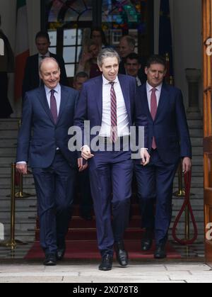 New Taoiseach Simon Harris (centre) with Tanaiste Micheal Martin (left) and Green Party Leader Eamon Ryan (right) ahead of a photocall with his newly appointed Ministers of State on the steps of the Government Buildings in Dublin. Picture date: Wednesday April 10, 2024. Stock Photo