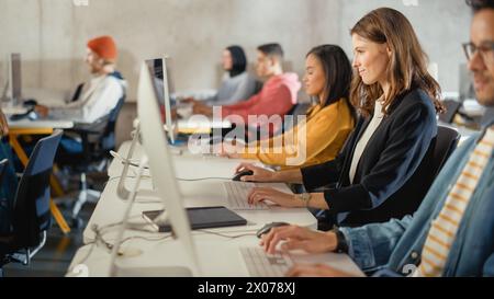 Diverse Multiethnic Group of Female and Male Students Sitting in College Room, Learning Computer Science. Young Scholars Study Information Technology on Computers in University, Writing Code in Class. Stock Photo