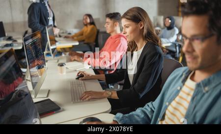 Diverse Multiethnic Group of Female and Male Students Sitting in College Room, Learning Computer Science. Young Scholars Study Information Technology on Computers in University, Getting Knowledgeable. Stock Photo