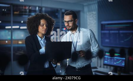 Modern Office: Successful Corporate CEO Working on Laptop and Consulting with Manager. Smiling Businesspeople Discuss Investment in Digital e-Commerce Startup. Portrait Shot. Stock Photo