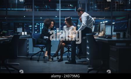 Diverse Team of Managers Working and Having Discussions in Big City Office in the Evening. Colleagues Talk, Discuss Business Opportunities, Evaluate Financial Reports, Plan Investment Strategy. Stock Photo