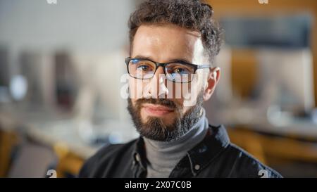 Portrait of a Happy Handsome Smart Male, Seriously Looking on Camera Indoors. Confident Successful Man Wears and Turtleneck and Glasses, Has a Bushy Beard and Short Curly Hair. Stock Photo