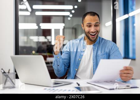 An Indian man in a home office setting exudes happiness while celebrating a business victory, reflecting success and positivity. Stock Photo