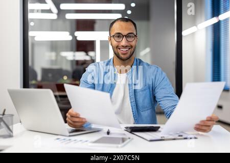 Professional Indian businessman analyzing documents in a contemporary office setting, focused and dedicated. Stock Photo