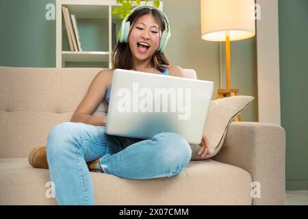 Smiling chinese young woman Working Online On Laptop At Home. Stock Photo