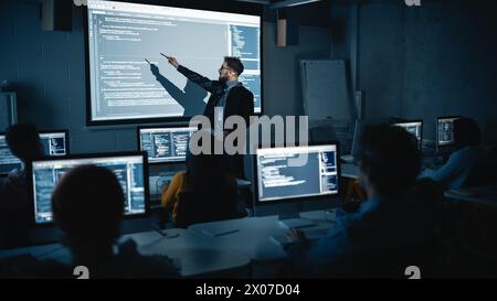 Teacher Giving Computer Science Lecture to Diverse Multiethnic Group of Female and Male Students in Dark College Room. Projecting Slideshow with Programming Code. Explaining Information Technology. Stock Photo