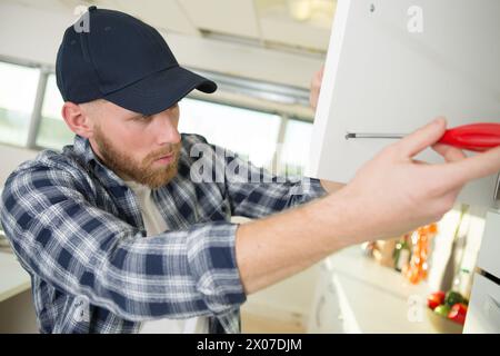 a worker installing cabinet doors Stock Photo