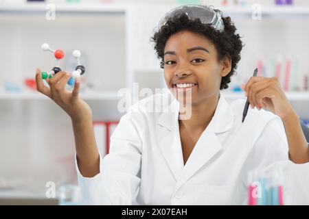 happy woman examining a 3d model of dna in lab Stock Photo