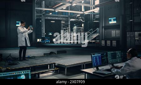 Male Engineer Uses Tablet Computer while Working in an Industial Facility at a Factory. Scientist uses Augmented Reality Software. Empty Space Left for Mock Up Template for VFX. Stock Photo